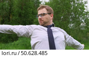 Confident Businessman in Natural Setting. Man stands in front of lush green backdrop. Remote working. Portrait of happy mid adult male wearing formal clothes, shirt and tie, glasses. Find inspiration. Стоковое видео, видеограф Марина Демидюк / Фотобанк Лори