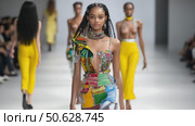 Black model in colorful patchwork dress walks eco-fashion runway. Стоковое AI-видео, аниматор Екатерина Усенко / Фотобанк Лори