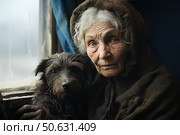 An emotional portrait of an elderly woman in a hood, sitting by a window in a dilapidated room with her faithful dog in her arms. The woman's face shows traces of a difficult life, fatigue and wisdom, and in her gaze - silence and deep humanity. The dog, with wet and disheveled fur, cuddles up to the owner, radiating devotion and anxiety. The atmosphere of the scene is cold, with dim light from the window, emphasizing the drama and intimacy of the moment. The photo is ideal for themes of compassion, loneliness, old age, loyalty, homelessness, life's trials and humanity. Стоковое AI-изображение, AI-художник Анна Кривицкая / Фотобанк Лори