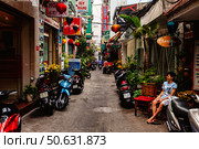 Narrow Street in Ho Chi Minh City Features Motorbikes and a Man Resting (2024 год). Редакционное фото, фотограф Aleksandr Golubev / Фотобанк Лори