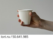 Hand holding white paper ripple cup on white background. Стоковое AI-изображение, AI-художник Иван Рябоконь / Фотобанк Лори