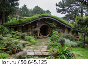 Cozy hobbit house nestled in a lush green garden. Стоковое AI-изображение, AI-художник Иван Рябоконь / Фотобанк Лори
