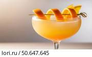 Elegant cocktail in a stemmed glass, adorned with curled citrus peel on a skewer garnish, displaying a gradient from deep orange to pale yellow, suggesting a refreshing taste. Стоковое AI-изображение, AI-художник Журавлева Кристина / Фотобанк Лори
