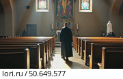 A monk in a dark robe walks down the central aisle of a church, illuminated by spiritual sunbeams streaming through the windows. Стоковое AI-видео, аниматор Sergey Grishin / Фотобанк Лори