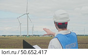 Inspector, gesturing actively with his hands, is inspecting wind farm to ensure that there are no errors in operation during power generation. Стоковое видео, видеограф Strunov David / Фотобанк Лори