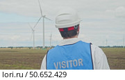 A wind farm inspector checks the operation of the turbines as they rotate in the wind to generate electricity. Стоковое видео, видеограф Strunov David / Фотобанк Лори