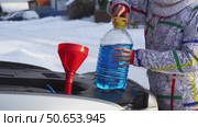 Driver pours glass fluid into car in winter. Стоковое видео, видеограф Igor Skripachev / Фотобанк Лори