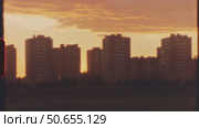 Super 8 mm - sunlight warming residential buildings, casting golden orange glow across urban landscape during tranquil twilight hours with serene cityscape atmosphere. Стоковое видео, видеограф Данил Руденко / Фотобанк Лори