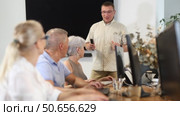 Middle-aged male instructor teaching computer skills to old students during IT classes. Стоковое видео, видеограф Яков Филимонов / Фотобанк Лори