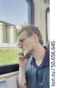 A man in dark glasses and a green shirt is sitting on a train. Стоковое видео, видеограф Ярославский Максим / Фотобанк Лори