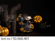 Halloween celebration. Black skull with golden roses, pumpkins, and black candles. Decor for the Day of the Dead or Halloween on a black background. Стоковое фото, фотограф Photojuli / Фотобанк Лори