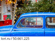 Concept of goods delivery. Christmas tree on the roof of a vintage blue Christmas car. Decorated New Year's Moscow 2026. Стоковое фото, фотограф Photojuli / Фотобанк Лори