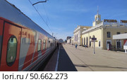 Railway platform of city station. People walk along platform while train is parked. Beautiful old station building. Russia, Yaroslavl, May 22, 2025. Редакционное видео, видеограф Ирина / Фотобанк Лори