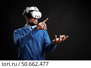 Virtual reality experience with a man interacting in a dark setting using advanced technology. Стоковое фото, фотограф Сергей Толмачёв / Фотобанк Лори