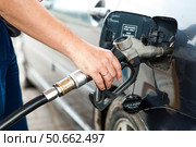 Gas station. A gas station attendant in a car's fuel tank. A man refuels a car with gasoline. Rising fuel prices worldwide. Стоковое фото, фотограф Photojuli / Фотобанк Лори