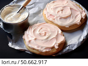 Pastry chef spreading pink frosting on freshly baked cookies. Стоковое AI-изображение, AI-художник Иван Рябоконь / Фотобанк Лори