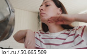Attractive brunette mid adult woman putting on makeup looking in the mirror. Beautiful lady caring her face. 40 years old female applied cosmetics. Natural beauty and aging concept. Skin care, make-up. Стоковое видео, видеограф Марина Демидюк / Фотобанк Лори