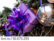 Holiday toys and purple gift boxes on the New Year's tree in Moscow. The concept of buying and giving gifts. New Year's card 2026. Стоковое фото, фотограф Photojuli / Фотобанк Лори
