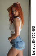 Confident Woman in Shorts and Stylish Outfit, With Vibrant Red Hair, Poses in a Minimalistic Setting. Fashion Photography. Стоковое AI-видео, аниматор Sergey Grishin / Фотобанк Лори
