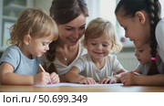 Joyful Kids Draw With a Smiling Woman at a Cozy Table in a Bright Room, Capturing Family Activities and Childcare. Стоковое AI-видео, аниматор Sergey Grishin / Фотобанк Лори