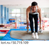 Male athlete doing complicated exciting trick on pommel horse in professional gym. Стоковое фото, фотограф Татьяна Яцевич / Фотобанк Лори