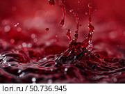 Crown shaped splash rising from red liquid surface with falling drops. Стоковое AI-изображение, AI-художник Иван Рябоконь / Фотобанк Лори