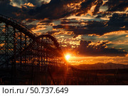Wooden rollercoaster silhouette at sunset with dramatic sky. Стоковое AI-изображение, AI-художник Иван Рябоконь / Фотобанк Лори