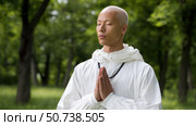 Buddhist monk praying in peaceful forest setting. Стоковое AI-изображение, AI-художник Юрий Поздников / Фотобанк Лори