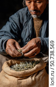 Herbalist holding dried herbs in hands over burlap sack. Стоковое AI-изображение, AI-художник Юрий Поздников / Фотобанк Лори