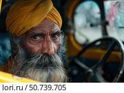 Bearded senior sikh man wearing yellow turban driving a rickshaw in india. Стоковое AI-изображение, AI-художник Иван Рябоконь / Фотобанк Лори