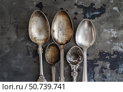 Five antique silver spoons resting on dark metal surface. Стоковое AI-изображение, AI-художник Иван Рябоконь / Фотобанк Лори