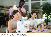 Positive girl working at machine during group sewing course for adults. Стоковое фото, фотограф Яков Филимонов / Фотобанк Лори