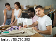 Multiethnic participants in coterie practice sewing, chatting, work textile and paper dress pattern. Стоковое фото, фотограф Яков Филимонов / Фотобанк Лори