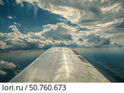 Airplane wing soaring through dramatic cloudscape. Стоковое AI-изображение, AI-художник Иван Рябоконь / Фотобанк Лори