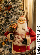 Santa Claus doll in a wicker basket on the background of the Christmas tree. Стоковое фото, фотограф Оксана Шведкова / Фотобанк Лори
