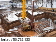 Строительство многоквартирного жилого дома в городе, строительная техника забивает сваи при строительстве фундамента (2023 год). Стоковое фото, фотограф Оксана Шведкова / Фотобанк Лори