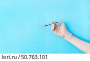 Male hand in transparent vinyl disposable glove holding syringe above blue background . Safety and selfcare concept. Стоковое фото, фотограф Акимова Надежда / Фотобанк Лори