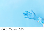 Human hands puting on blue nitrile disposable glove above light blue background. Safety first concept. Стоковое фото, фотограф Акимова Надежда / Фотобанк Лори