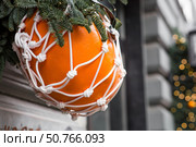 Happy New Year 2026. Mandarins in a string bag and Christmas tree decorations on the streets of Moscow. The concept of preparing decorations and ornaments for Christmas. Стоковое фото, фотограф Photojuli / Фотобанк Лори