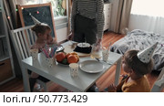 Children Eating Birthday Cake Slice on a Birthday Party at Home. Siblings, girls and a boy together celebrating a party, eating cake sitting at festive table. Little Kid Celebration. Surprise. Low key. Стоковое видео, видеограф Марина Демидюк / Фотобанк Лори