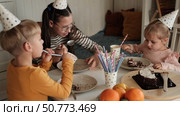 Children Eating Birthday Cake Slice on a Birthday Party at Home. Siblings, girls and a boy together celebrating a party, eating cake sitting at festive table. Little Kid Celebration. Surprise. Low key. Стоковое видео, видеограф Марина Демидюк / Фотобанк Лори
