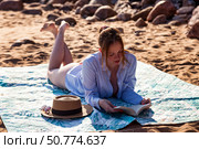 Reading a Captivating Book on a Sunny Beach While Enjoying the Gentle Ocean Breeze. Стоковое фото, фотограф Aleksandr Golubev / Фотобанк Лори