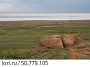 Fancy stones on the slopes of Bolshoe Bogdo Mountain and the salt lake Baskunchak in the distance on a summer day, Bogdinsko-Baskunchak Nature Reserve, Akhtubinsky district, Astrakhan region, Russia. Стоковое фото, фотограф Ula Ulachka / Фотобанк Лори