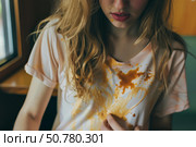 Woman looking at food stain on her t shirt after a clumsy meal. Стоковое AI-изображение, AI-художник Иван Рябоконь / Фотобанк Лори