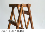 Wooden folding step stool standing on white background. Стоковое AI-изображение, AI-художник Иван Рябоконь / Фотобанк Лори