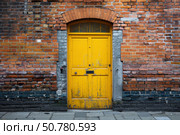 Yellow door breaking the monotony of old brick wall. Стоковое AI-изображение, AI-художник Иван Рябоконь / Фотобанк Лори