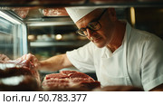 Chef skillfully inspects high-quality cuts of meat in a well-lit butcher shop. Стоковое AI-изображение, AI-художник Сергей Толмачёв / Фотобанк Лори
