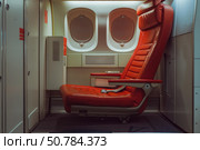Empty red seat standing in the middle of an airplane cabin. Стоковое AI-изображение, AI-художник Иван Рябоконь / Фотобанк Лори