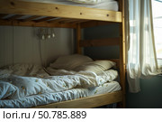 Unmade bunk bed by the window in sunny morning. Стоковое AI-изображение, AI-художник Иван Рябоконь / Фотобанк Лори