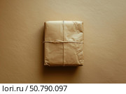 Wrapped package tied with string on brown background symbolizing simplicity. Стоковое AI-изображение, AI-художник Иван Рябоконь / Фотобанк Лори